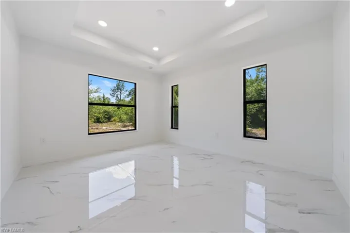 Spare room featuring baseboards, recessed lighting, marble finish floor, and a healthy amount of sunlight