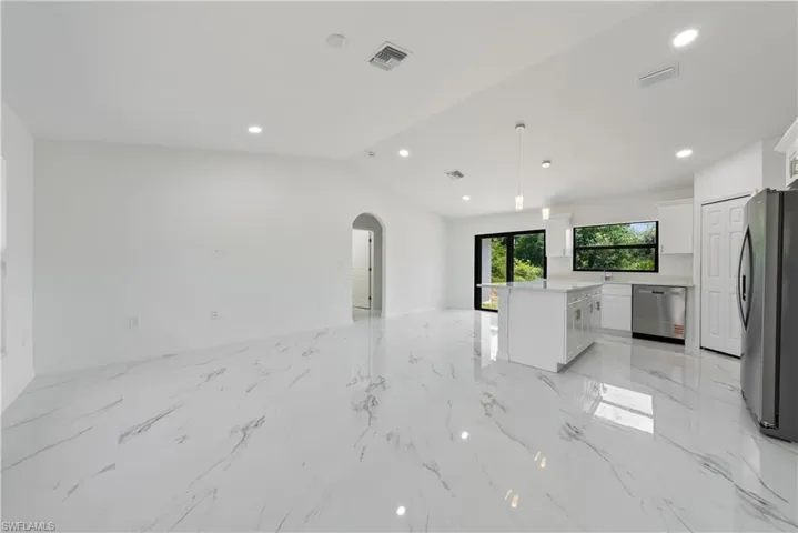 Unfurnished living room featuring arched walkways, visible vents, marble finish floor, and lofted ceiling