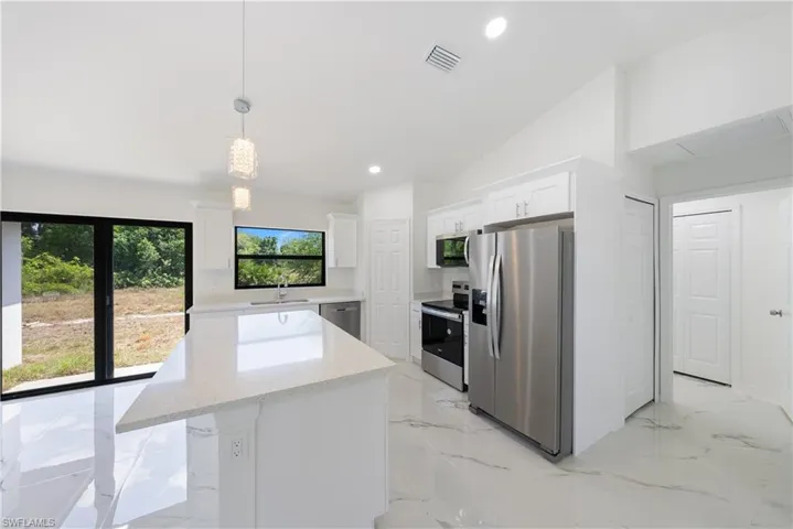 Kitchen featuring white cabinets, visible vents, a kitchen island, appliances with stainless steel finishes, and a sink