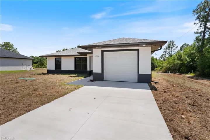 View of front facade featuring an attached garage, roof with shingles, driveway, and stucco siding