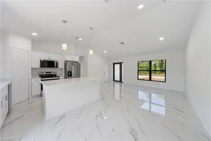 Kitchen with appliances with stainless steel finishes, white cabinetry, recessed lighting, marble finish floor, and lofted ceiling