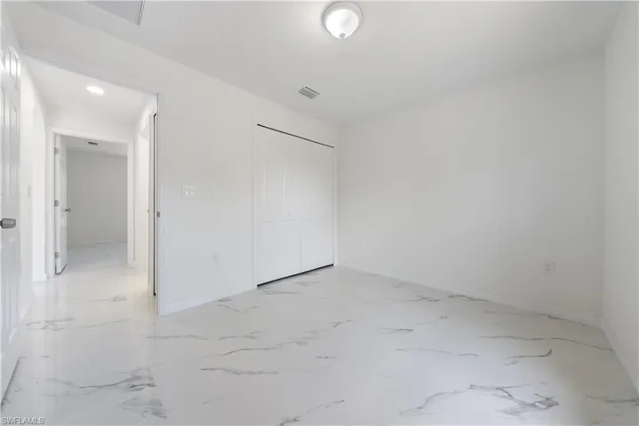 Unfurnished bedroom featuring a closet, visible vents, marble finish floor, and baseboards