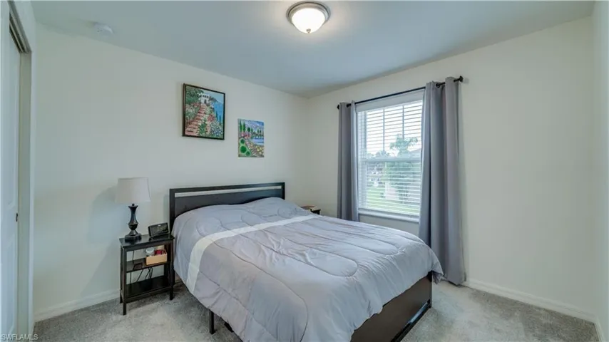 Bedroom with light colored carpet and baseboards