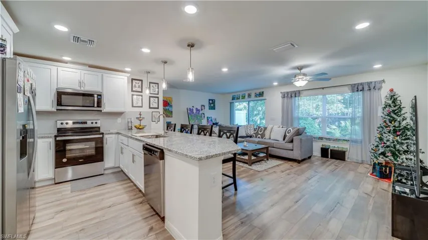 Kitchen with stainless steel appliances, a peninsula, a kitchen breakfast bar, white cabinets, and recessed lighting