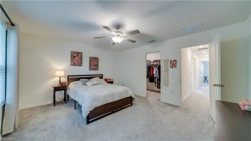 Bedroom with a walk in closet, carpet flooring, and a ceiling fan