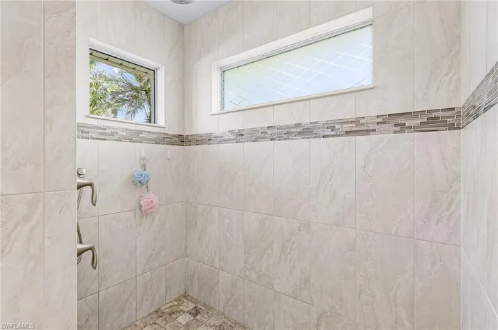 The Primary Bath has floor-to-ceiling tile for ease of cleaning with no glass door.