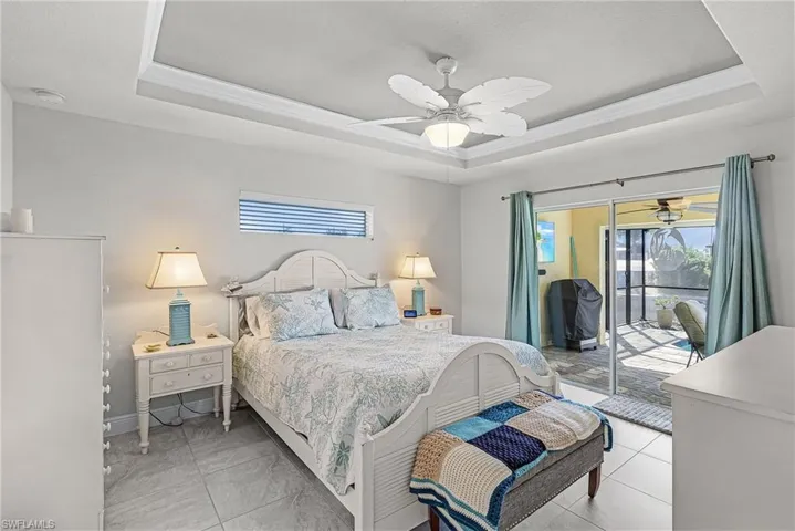 The primary bedroom has tile floors and sliders leading to the pool area.