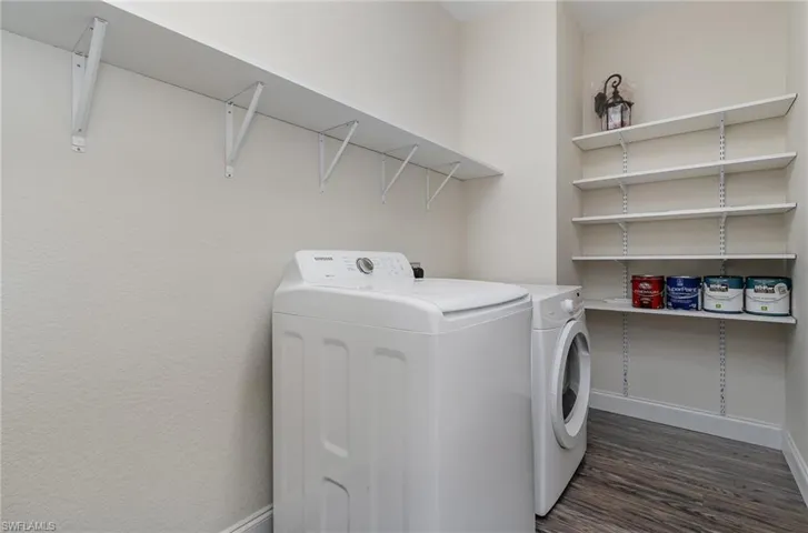Washroom featuring dark hardwood / wood-style flooring and washing machine and clothes dryer