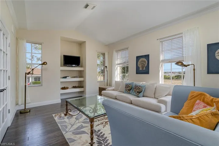 Living room with dark wood-type flooring, lofted ceiling, a healthy amount of sunlight, and built in shelves
