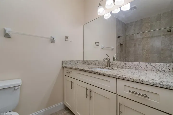 Bathroom with vanity, tiled shower, and toilet