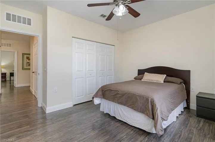 Bedroom featuring ceiling fan, dark hardwood / wood-style floors, and a closet