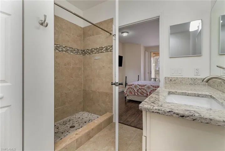 Bathroom with vanity, tile patterned flooring, and a tile shower