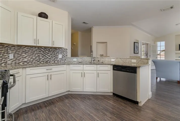 Kitchen featuring stainless steel appliances, white cabinetry, light stone counters, and kitchen peninsula