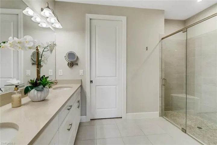 Primary bath with tile patterned flooring, double vanity, and a shower stall and private toilet area
