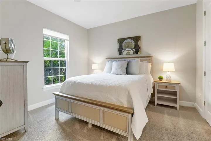 Bedroom featuring light carpet, walk-in closet, ceiling fan and western window with direct access to bathroom