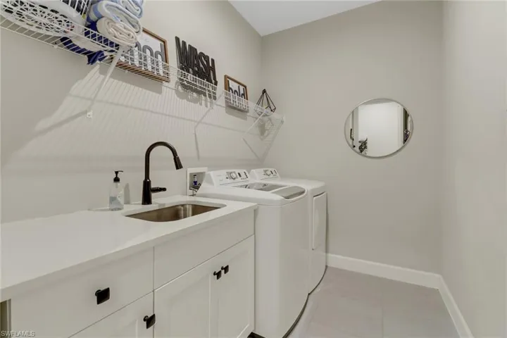 Laundry area featuring independent washer and dryer, sink, cabinet space, and light tile patterned floors