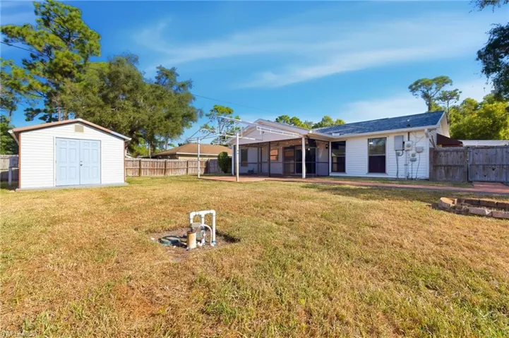 Fenced backyard with a sunroom, a storage shed, and a patio