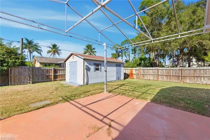 Fenced backyard featuring a patio area, a sunroom, a lanai, and a storage shed