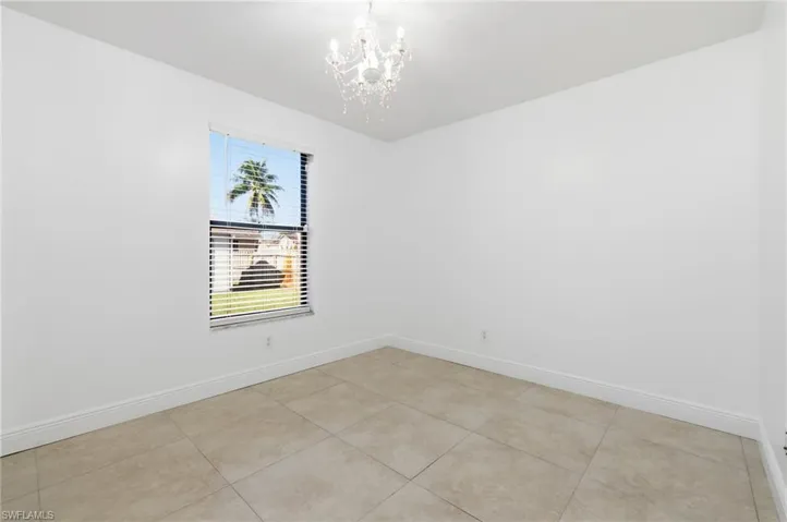 Empty room with suspended lighting and light tile patterned flooring