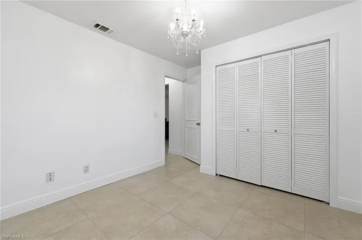 Unfurnished bedroom with hanging lights, light tile patterned floors, and a closet