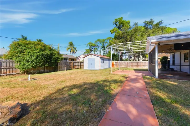 Fenced backyard featuring a sunroom, a shed, and a ceiling fan