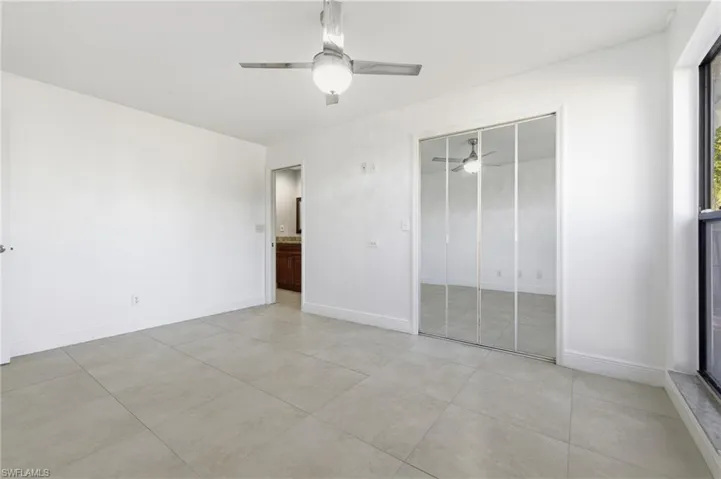 Unfurnished bedroom with a ceiling fan, a closet, light tile patterned flooring, and ensuite bathroom