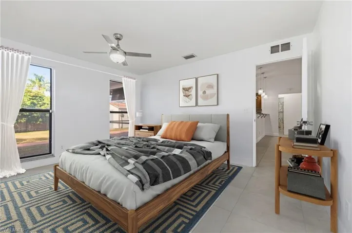 Tiled bedroom with a ceiling fan and baseboards