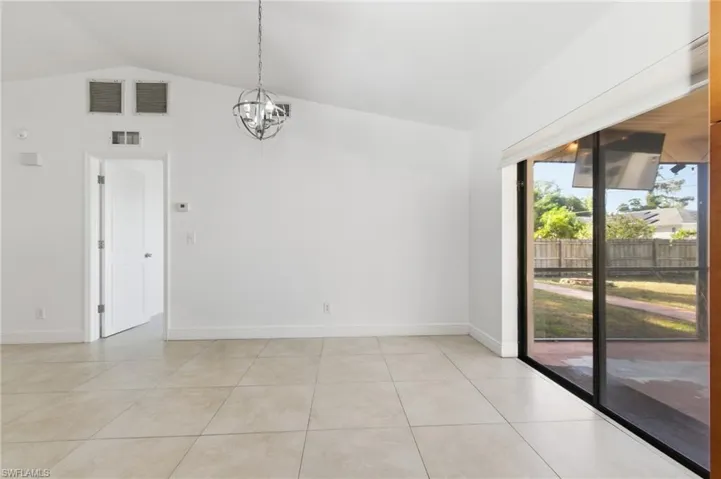 Spare room featuring lofted ceiling, hanging lights, and light tile patterned flooring