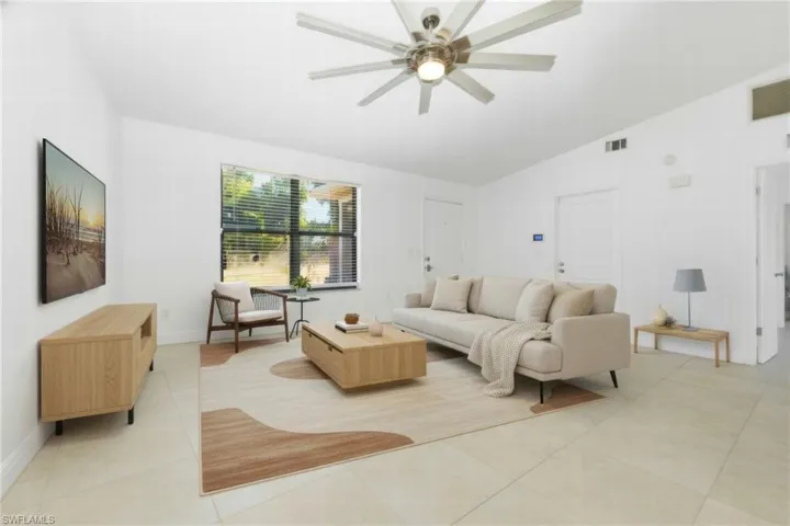 Living room featuring vaulted ceiling, light tile patterned floors, and ceiling fan