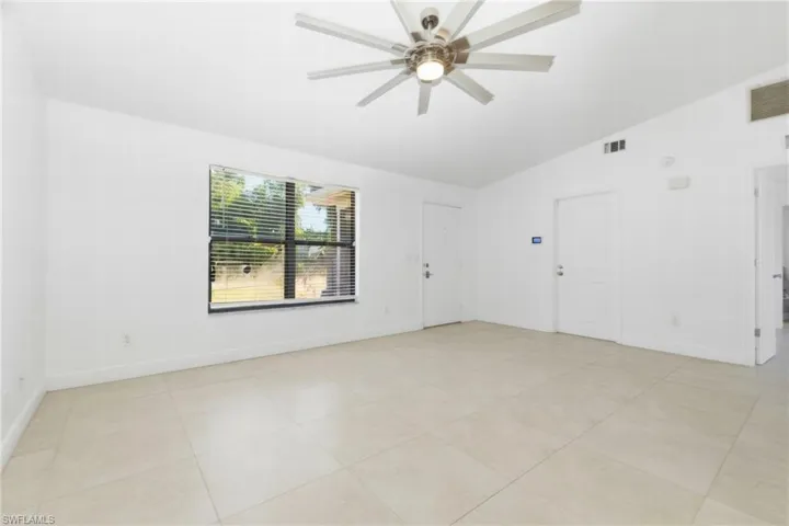 Spare room featuring vaulted ceiling, light tile patterned flooring, and a ceiling fan