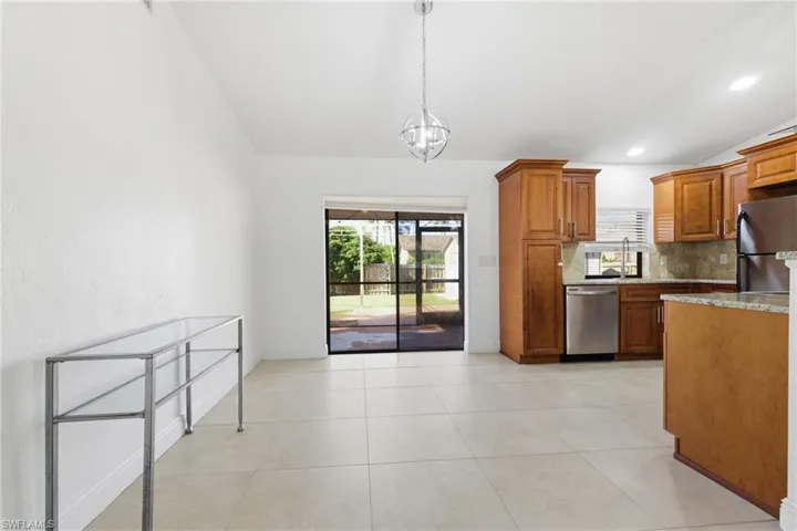 Kitchen with wood finish cabinets, vaulted ceiling, stainless steel appliances, light stone counters, and backsplash