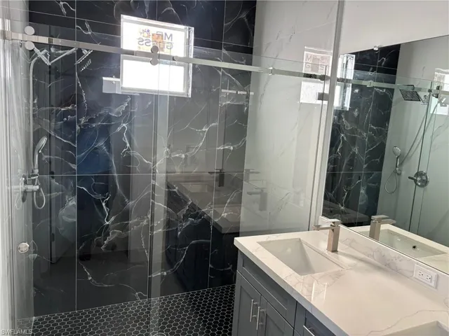 Bathroom with a marble finish shower and vanity