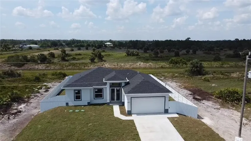 View of front of home featuring a garage, driveway, a shingled roof, and a view of rural / pastoral area
