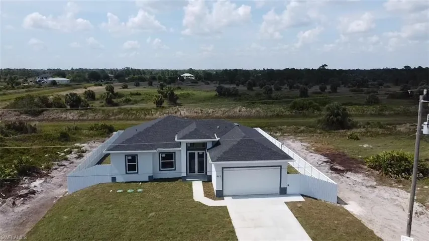 View of front of property featuring a garage, concrete driveway, and roof with shingles