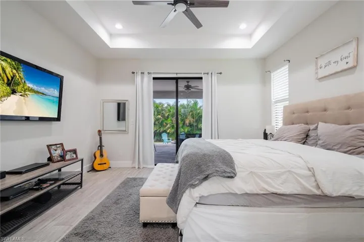 Bedroom featuring access to exterior, ceiling fan, a raised ceiling, and light hardwood / wood-style floors