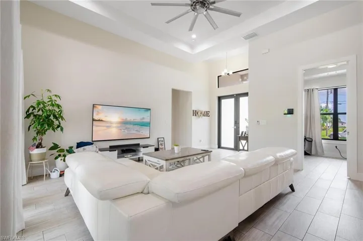 Living room featuring french doors, ceiling fan, a raised ceiling, and a towering ceiling