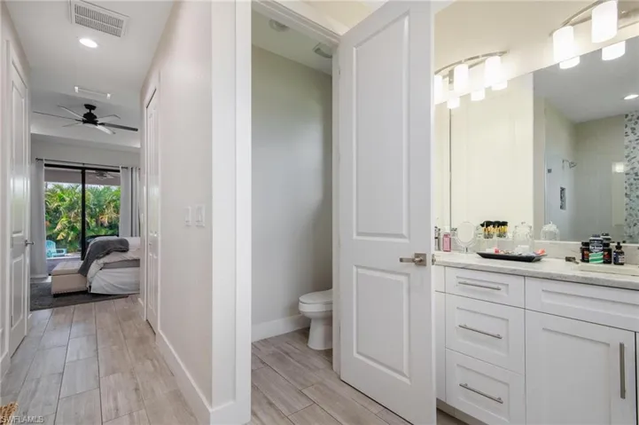 Bathroom featuring vanity, wood-type flooring, ceiling fan, a shower, and toilet