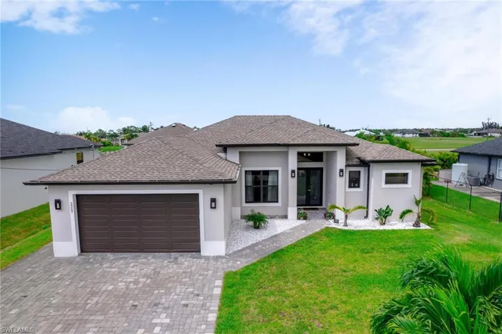 View of front of property with a garage and a front lawn