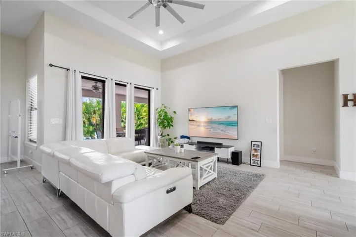 Living room featuring ceiling fan, a raised ceiling, and a towering ceiling
