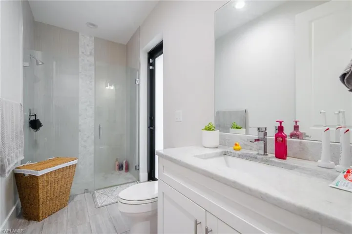Bathroom featuring tile patterned floors, a shower with door, toilet, and vanity