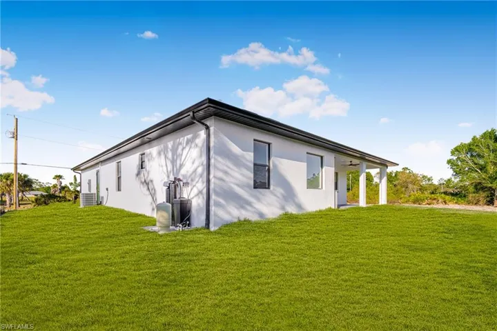 View of side of home with central AC unit, a lawn, and stucco siding