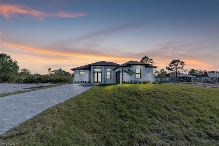 View of front of property with a yard and decorative driveway