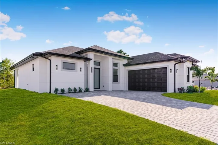 Prairie-style home featuring stucco siding, a front lawn, decorative driveway, and a garage