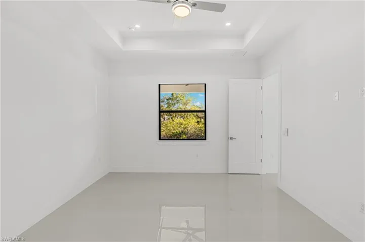 Unfurnished room with baseboards, a tray ceiling, and a ceiling fan