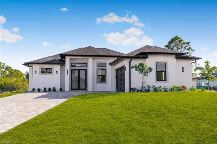 Prairie-style house featuring a front lawn, an attached garage, french doors, and stucco siding