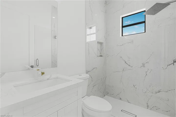 Bathroom featuring a marble finish shower, toilet, and vanity