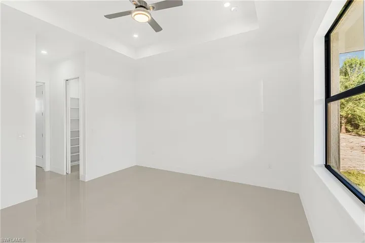 Spare room featuring a ceiling fan, a tray ceiling, recessed lighting, and baseboards