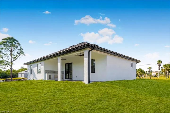 Rear view of property with a yard, ceiling fan, and stucco siding