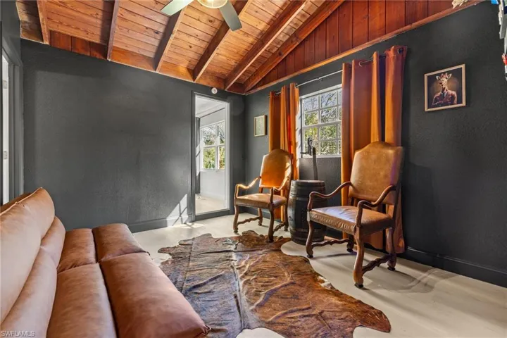 Living area featuring wooden ceiling, ceiling fan, and a textured wall