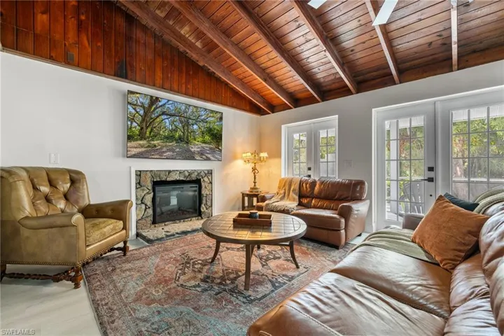 Living area with wood ceiling, a skylight, a fireplace, french doors, and light wood-type flooring